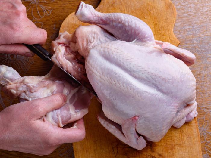 Hands cutting up a whole chicken